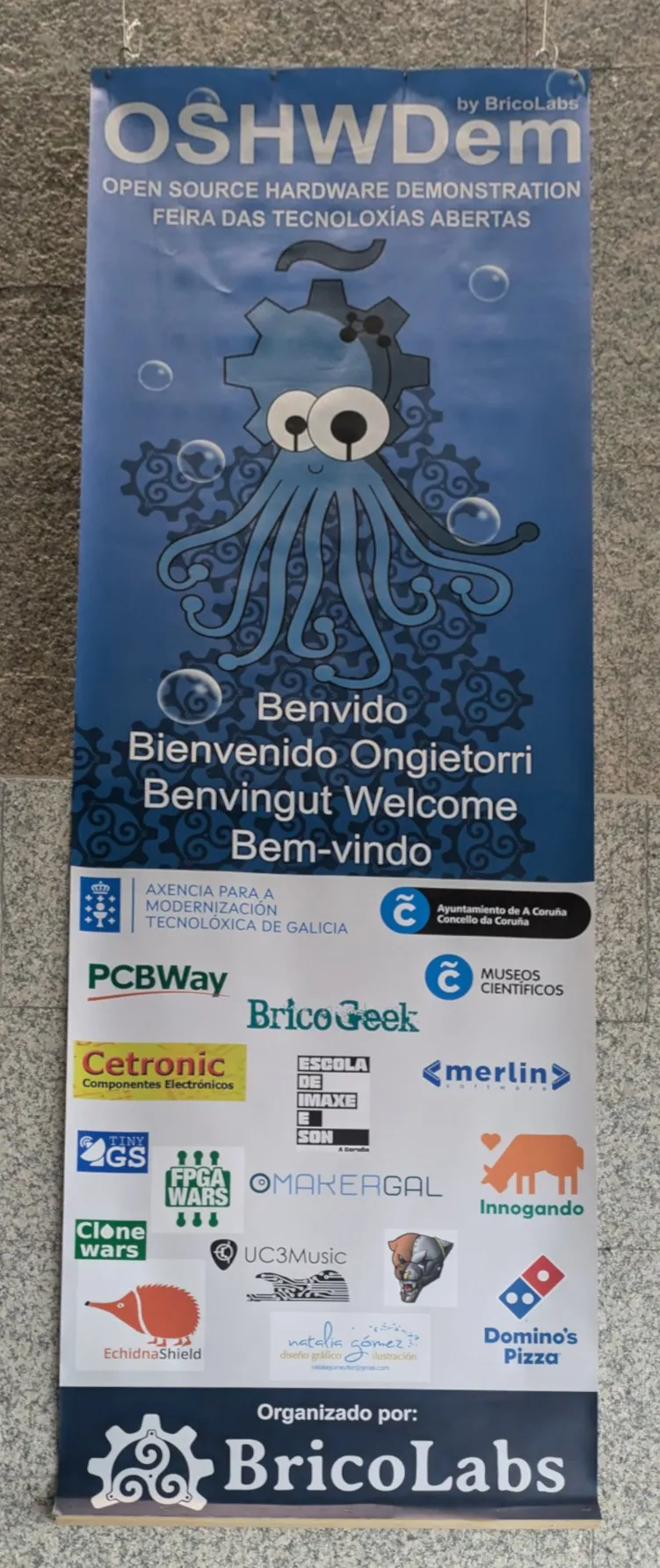 Cartel de bienvenida de la OSHWDem, con su pulpo y los logos de los patrocinadores.